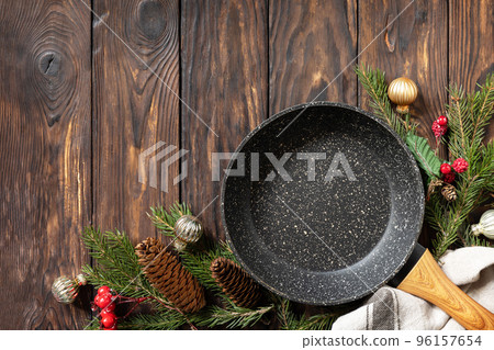 Empty cooking frying pan with tablecloth, Christmas tree and decor on wooden background. Flat mock up for design. View from above. Copy space. Empty cooking frying pan with tablecloth, Christmas tree and decor on wooden background. Flat mock up for design. View from above. Copy space. 96157654