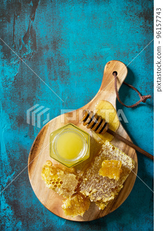 Natural Honey. Honey in glass jar and dipper, Sweet Honeycombs on blue stone table. Top view flat lay background. Copy space. Natural Honey. Honey in glass jar and dipper, Sweet Honeycombs on blue stone table. Top view flat lay background. Copy space. 96157743