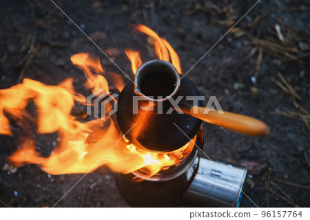 Cooking coffee in cezve on bonfire in camping Cooking coffee in cezve on bonfire in camping 96157764