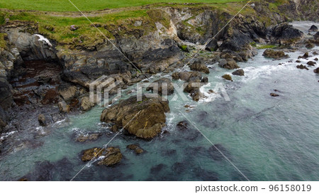 Tidal waves of the Atlantic Ocean near the southern coast of the island of Ireland. Rocky seashore. Seascape, top view. View from above. Tidal waves of the Atlantic Ocean near the southern coast of the island of Ireland. Rocky seashore. Seascape, top view. View from above. 96158019