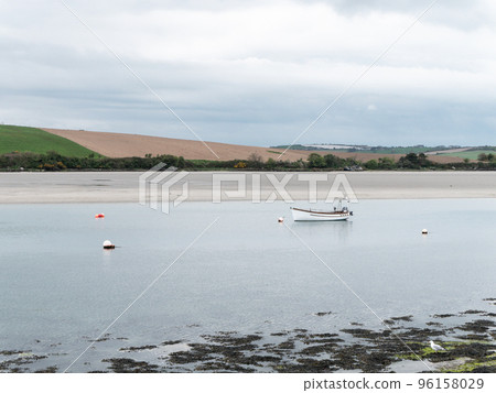 A motor boat moored in shallow water. Calm water surface. Picturesque hills on the shore of the bay. The sandy shore of the Atlantic Ocean. 96158029