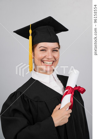 Smiling woman in graduation gown holding diploma on white background. Vertical photo. 96158554