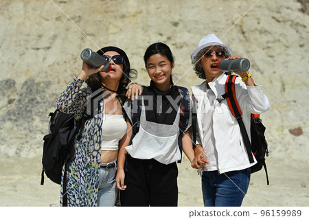 Two active middle aged women and teenage girl resting, standing front of rock cliff walls. People and outdoor activity concept 96159989