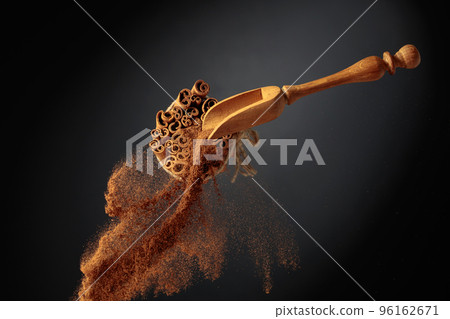 Cinnamon powder is poured out of the wooden spoon. Cinnamon powder is poured out of the wooden spoon. 96162671