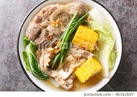 Bulalo is a beef dish from the Philippines soup made by cooking beef shanks and bone marrow with cabbage, corn, scallions, onions, garlic and fish sauce closeup. Horizontal top view Bulalo is a beef dish from the Philippines soup made by cooking beef shanks and bone marrow with cabbage, corn, scallions, onions, garlic and fish sauce closeup. Horizontal top view 96162697