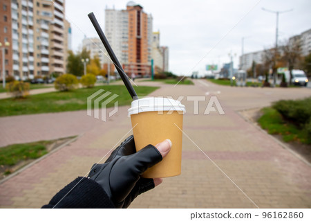 Paper cup with coffee in hand on backdrop of city Paper cup with coffee in hand on backdrop of city 96162860