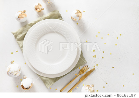 Beautiful Christmas festive table setting with white plate, golden balls on white. Beautiful Christmas festive table setting with white plate, golden balls on white. 96165197