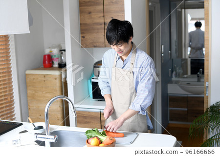 穿著圍裙在廚房做飯的年輕人 穿著圍裙在廚房做飯的年輕人 96166666
