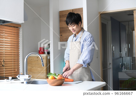 穿著圍裙在廚房做飯的年輕人 穿著圍裙在廚房做飯的年輕人 96166667