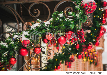 Building front decorated to Christmas with christmas trees fir branches, decorations and garland lights - festive and winter holidays concept 96167048