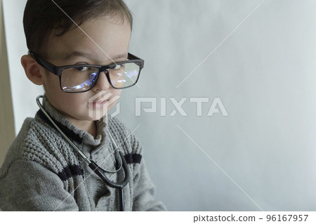 a little boy with glasses and a stel on his head, looking at the camera while he is wearing a stel a little boy with glasses and a stel on his head, looking at the camera while he is wearing a stel 96167957
