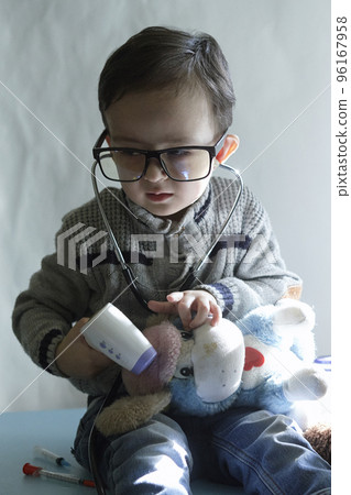 a little boy playing with his stuffed animals and drinking milk from a bottle while sitting on a blue table next to him 96167958