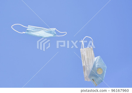 two surgical masks flying in the air with one being attached to it's side and another hanging from its mouth two surgical masks flying in the air with one being attached to it's side and another hanging from its mouth 96167960