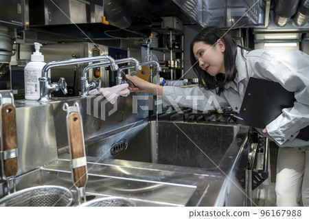 A young woman checking the kitchen, a commercial stainless steel sink, a commercial sink 96167988