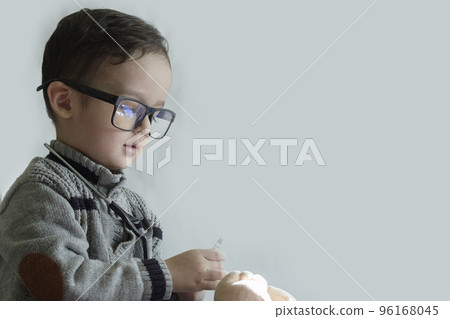 a young boy wearing glasses and playing with a remote control device in front of his face, against a white wall a young boy wearing glasses and playing with a remote control device in front of his face, against a white wall 96168045
