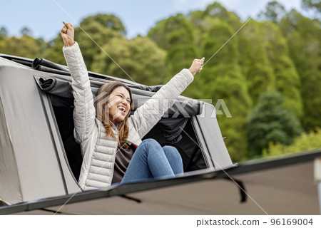 Asian woman sitting outside the tent above the campervan 96169004