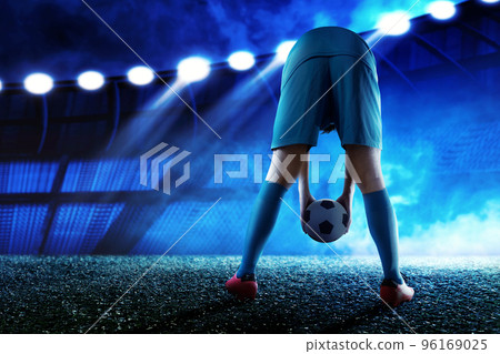 The rear view of a football player man in a blue jersey putting the ball 96169025