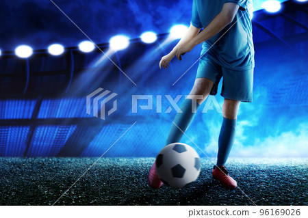 Football player man in a blue jersey kicking the ball 96169026