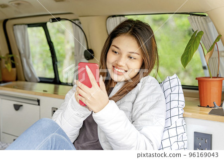 Asian woman using mobile phone inside the campervan Asian woman using mobile phone inside the campervan 96169043