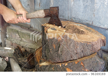 Cutting wood with a large sharp ax, Man Chops firewood, Chopping of wood on a wooden log in summer at the home Cutting wood with a large sharp ax, Man Chops firewood, Chopping of wood on a wooden log in summer at the home 96169169