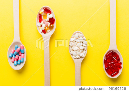 Vitamin capsules in a spoon on a colored background. Pills served as a healthy meal. Red soft gel vitamin supplement capsules on spoon Vitamin capsules in a spoon on a colored background. Pills served as a healthy meal. Red soft gel vitamin supplement capsules on spoon 96169326