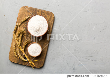 Flat lay of Wheat flour in wooden bowl with wheat spikelets on colored background. world wheat crisis 96169656