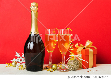 Champagne bottle with confetti, glasses and christmas decor on colored holiday background. Flat lay New Year decorations 96169666