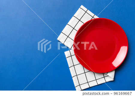 Top view on colored background empty round red plate on tablecloth for food. Empty dish on napkin with space for your design Top view on colored background empty round red plate on tablecloth for food. Empty dish on napkin with space for your design 96169667