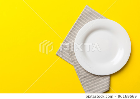 Top view on colored background empty round white plate on tablecloth for food. Empty dish on napkin with space for your design Top view on colored background empty round white plate on tablecloth for food. Empty dish on napkin with space for your design 96169669