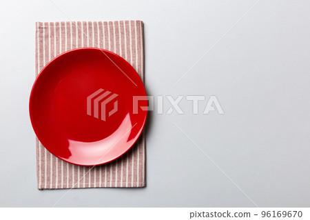 Top view on colored background empty round red plate on tablecloth for food. Empty dish on napkin with space for your design Top view on colored background empty round red plate on tablecloth for food. Empty dish on napkin with space for your design 96169670