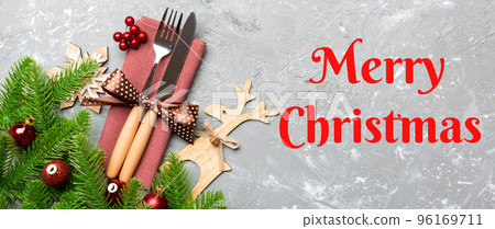 Merry Christmas text. Top view of flatware tied up with ribbon on napkin on cement background. Banner Christmas decorations and reindeer with empty space for your design. New Year holiday concept Merry Christmas text. Top view of flatware tied up with ribbon on napkin on cement background. Banner Christmas decorations and reindeer with empty space for your design. New Year holiday concept 96169711