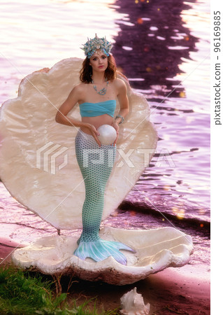 A beautiful mermaid girl stands in a large white shell 96169885