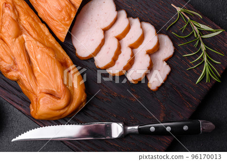 Tasty smoked fillet of chicken breast with spices and herbs on a wooden cutting board 96170013