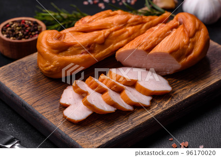 Tasty smoked fillet of chicken breast with spices and herbs on a wooden cutting board 96170020