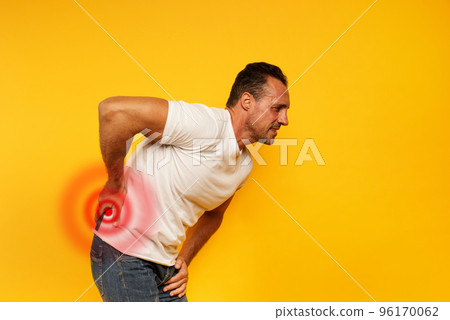 Aching man with back pain. Yellow background Aching man with back pain. Yellow background 96170062