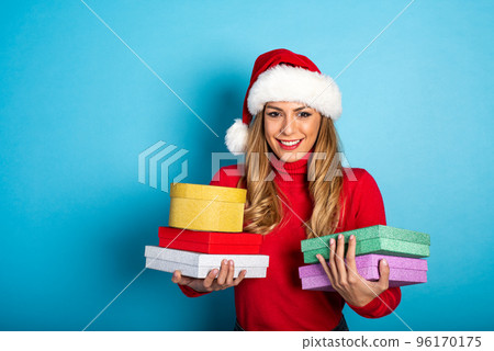 Happy girl with Christmas hat receives a lot of presents. Cyan background 96170175