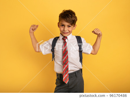 Young boy student acts like a muscled man. Yellow background Young boy student acts like a muscled man. Yellow background 96170486