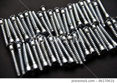 Shiny steel bolts for fixing furniture. Accessories on a black background. 96170618