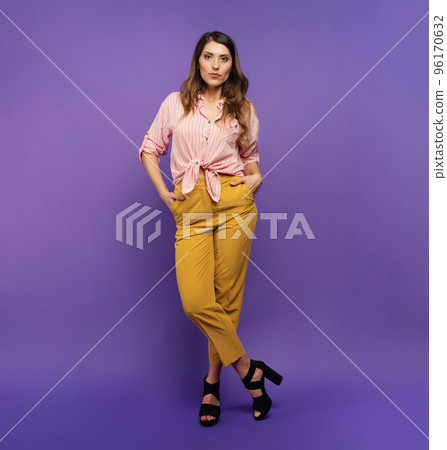 Brunette girl with a yellow and pink clothes over a purple background. concept of fashion and shopping Brunette girl with a yellow and pink clothes over a purple background. concept of fashion and shopping 96170632