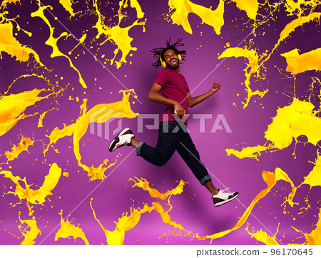 Boy with yellow headset listens to music and dances. emotional and energetic expression. Color spray effect Boy with yellow headset listens to music and dances. emotional and energetic expression. Color spray effect 96170645