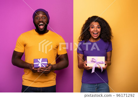 Happy and joyful couple show their Christmas present. Violet and yellow background 96171292