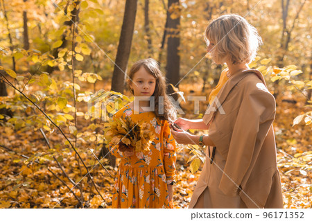 Worried mom looking at offended little daughter after family argument in autumn nature, mother and female child suffering misunderstanding and conflicts at home, problems between child and parent 96171352