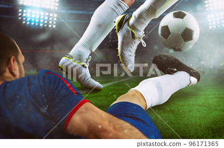 Football scene at night match with close up of two soccer players during a game match at the stadium 96171365