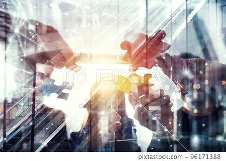 Business people join puzzle pieces in office. Concept of teamwork and partnership. double exposure with light effects 96171388