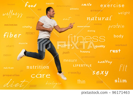 Sport man jumps on a yellow background. Happy and joyful expression. With most important fitness and diet terms 96171463