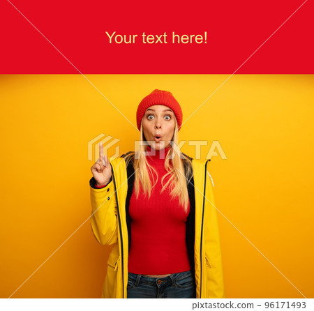 Girl indicates a message above. Amazed and shocked expression. Blank space for your text. Yellow background 96171493