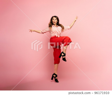 Brunette girl with red clothes jumps over a pink background. Concept of fashion and shopping with joyful expression 96171910