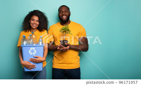 Happy couple hold a plastic container and a small tree over a light blue color. Concept of forestation, ecology, conservation, recycling and sustainability 96171957