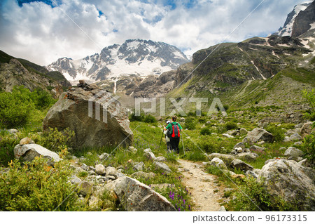 Women with backpacks and scandinavian sticks climb the mountains 96173315