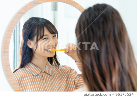 Young woman in pajamas brushing teeth 96173524